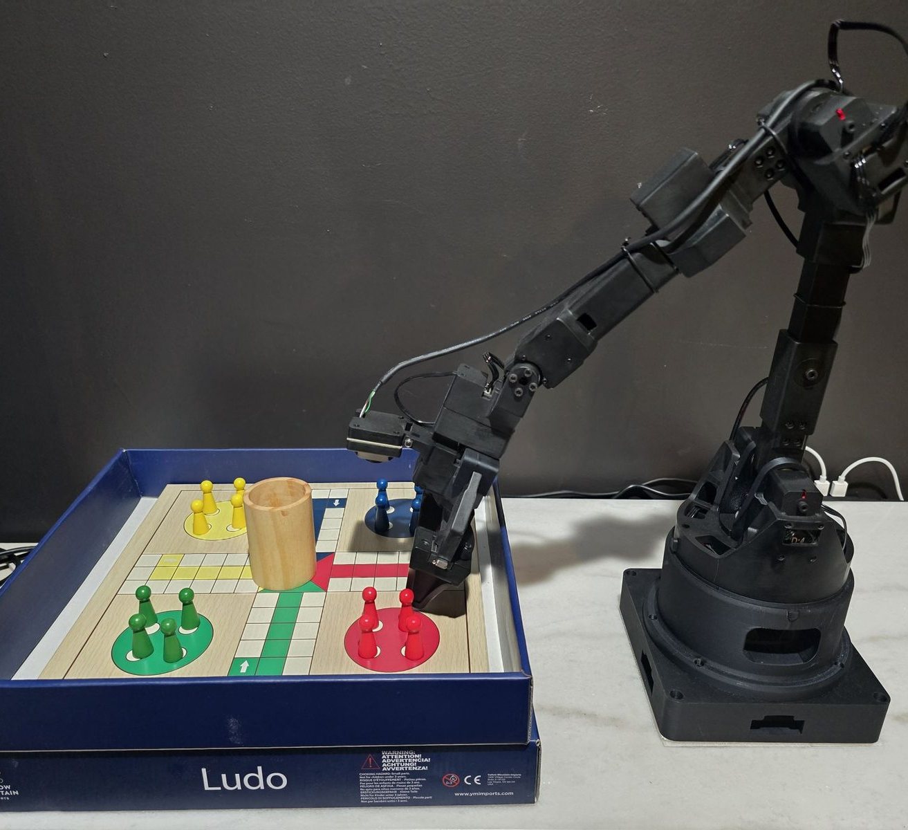 The lab's robot arm at the same Ludo board, in Isaac Sim and in the real world: real photo